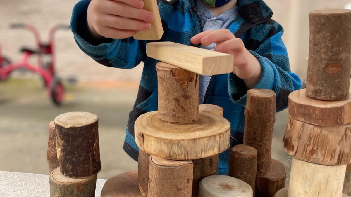 Child building structure with small logs | Samis Foundation in WA